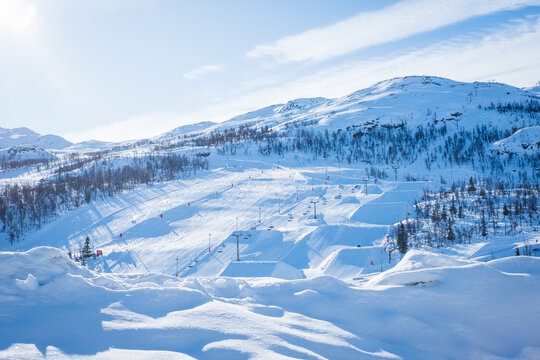 View over ski resort with slopes, chair lifts and majestic snowy mountains during winter day. Hemsedal ski center in Norway.