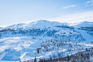 View over ski resort with slopes, chair lifts and majestic snowy mountains during winter day. Hemsedal ski center in Norway.