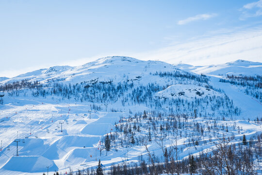 View over ski resort with slopes, chair lifts and majestic snowy mountains during winter day. Hemsedal ski center in Norway.