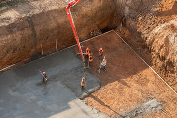 Above view of workers pouring concrete at foundation construction site