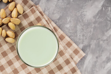 Pistachio milk in a glass on a gray concrete background. Organic lactose free pistachio milk and pistachios. Top view. Copy space