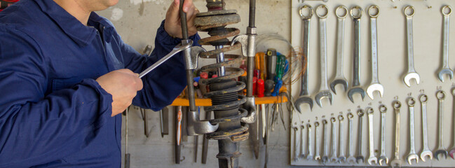 Image of the hands of a mechanic in his workshop holding a wrench and using extractors to...