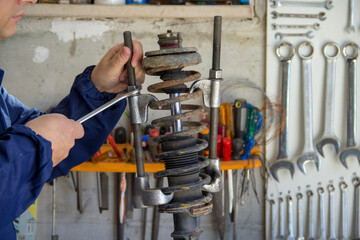 Image of the hands of a mechanic in his workshop holding a wrench and using extractors to...