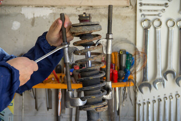 Image of the hands of a mechanic in his workshop holding a wrench and using extractors to...