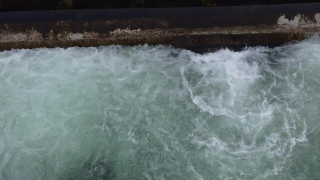 Overhead view of water flowing and swirling below a small dam