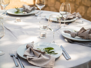 Wedding banquet concept. Chairs and round table for guests, served with cutler and, flowers and crockery and covered with a tablecloth