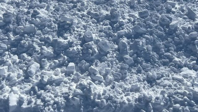 Slow pan across clumps of pure white snow and shadows
