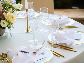 Beautiful outdoor wedding decoration in city. Candles and dried flowers and accessories with bouquets and glasses on table with linen tablecloth on newlywed table on green lawn