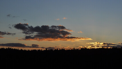 Fototapeta premium Natural sunset over the forest. Bright dramatic sky and dark earth. The sun above the horizon, horizon.