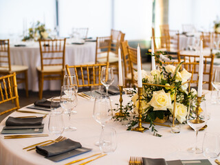 Table at luxury wedding reception event. Beautiful flowers on table and serving dishes and glasses and decoration