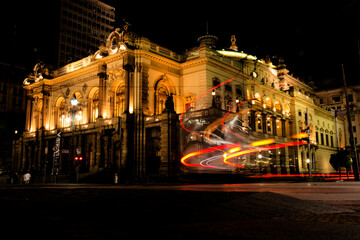 Prédio do teatro Municipal de São Paulo, a noite com rastros de luz dos carros em movimento. 