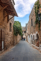 Street view of old town of Rhodes, Greece. Paved roads and pavements with colorful houses and fragrant flowers.