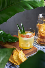 Special cocktail of pineapple, rum and mezcal with garnish chili and pineapple plants garnished with dried fruit in a kitchen with plants