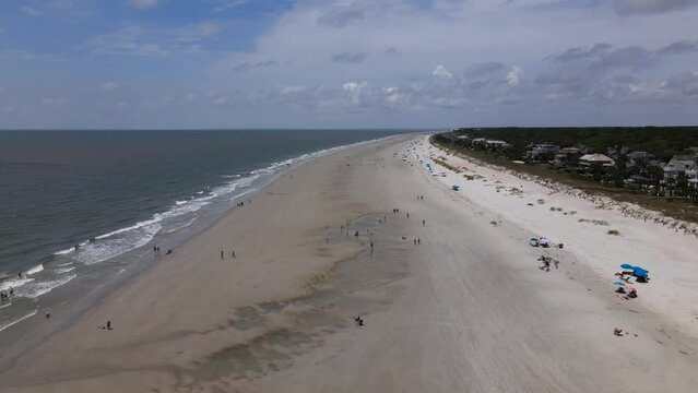 2022 - Excellent aerial footage of waves lapping the shores of Hilton Head, South Carolina as tourists walk the beach.