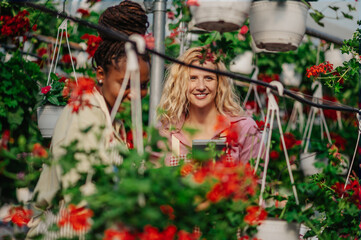 Multiracial woman gardeners working in a greenhouse and using tablet