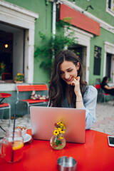 Beautiful woman sitting in a street cafe and using a laptop