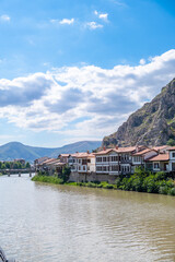 Fototapeta na wymiar View of old Ottoman houses on the banks of Yesilirmak river in Amasya city. Amasya landscape beautiful river with clouds, sunny summer day. Popular tourist destination in Turkey
