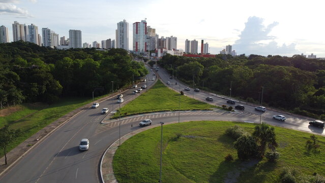Image of an avenue in Cuiaba, Mato Grosso - Brazil showing a large green vegetation and buildings in the background.