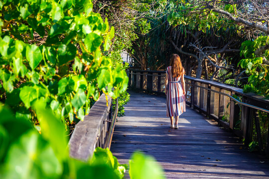 A girl in dress walks along the boardwalk and enjoys the view of the stunning Coolum Beach. Stunning panorama of Sunshine Coast, Queensland, Australia