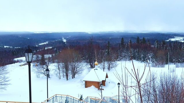 View of the chapel near the Belogorsky St. Nicholas Orthodox Missionary Monastery. Winter forest. The temple on the hill in winter. Russia, Perm Krai, Belaya Gora. 4K