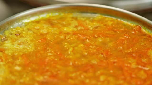 Boiling lentil soup close up. Cooking process red lentil soup. Traditional lebanese or arabic lentil and vegetable spicy soup. Static shot