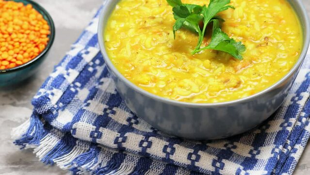 Red Lentil Soup with ingredients on a gray background. Bowl of lentil soup and a wooden spoon on a linen napkin. Tilt up camera movement