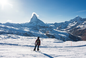 Young man snowboarding in Zermatt ski resort right next to the famous Matterhorn peak. Beautiful...