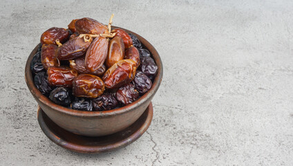 Various type of dried dates fruits in brown bowl over marble texture background