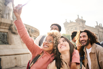 Young multiracial friends taking a selfie with smartphone and having fun in the city outdoors. High quality photo