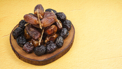 Fresh various dates fruits (kurma) over yellow background
