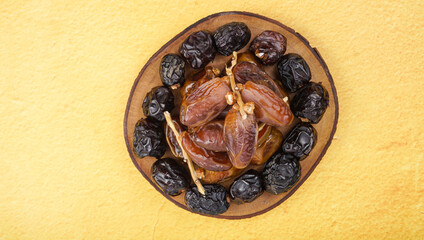 Fresh various dates fruits (kurma) over yellow background
