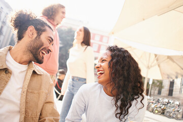 Heterosexual couples flirting outdoors on the terrace of a bar. Multiracial group of guys and girls meet through dating apps. High quality photo