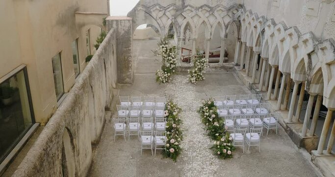 Decorated white chairs for guests near colonnaded gallery