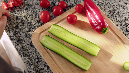 Top down view female hands cut green fresh cucumber on board close-up. Preparing salad and vegetables for vegetarian at home in kitchen. chef chop ingredients into salad.