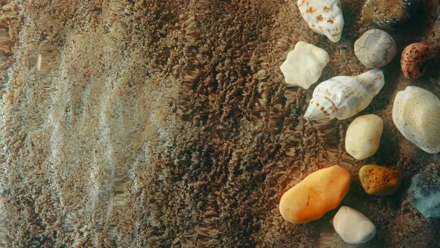 Top down view seabed background, sea floor beach sand ripple of water waves reflection, shells and stones. Sandy bottom surface summer. Underwater seafloor close-up. Place for title or logo