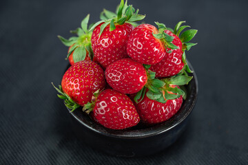 Strawberries in a black cup on black background