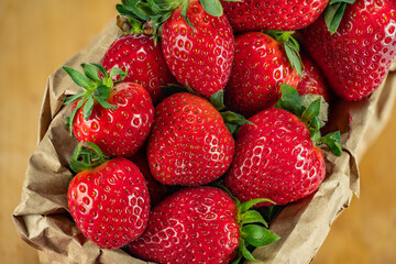 Strawberries in a basket of craft paper in a white background.