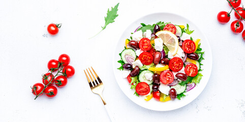 Greek salad with feta cheese, kalamata olives, cherry tomato, yellow paprika, cucumber and onion, healthy mediterranean diet food, low calories eating. White table background, top view