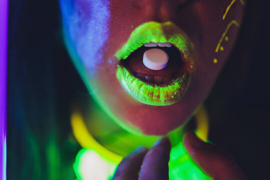 beautiful girl with lsd on tongue in nightclub with pink smoke.