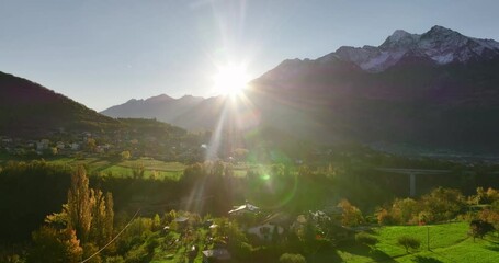 Rising Aerial Aosta Valley countryside with Italian Alps Mountain landscape at Sunrise with lens flare
