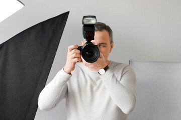 Mature photographer with professional camera working in studio