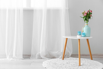 Vase with beautiful alstroemeria flowers and candles on table in room