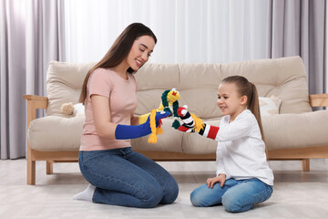 Happy mother and daughter playing with funny sock puppets together at home