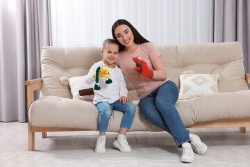 Happy mother and daughter playing with funny sock puppets together at home