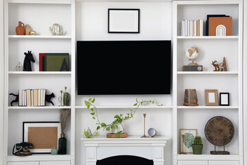 Stylish shelves with different decor elements and TV set in living room. Interior design