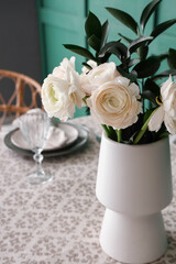 Vase with ranunculus flowers on dining table in room, closeup