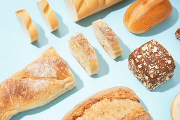 Fresh loaves of different bread on blue background