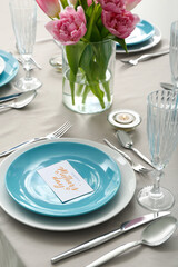 Setting for Mother's Day celebration and vase with tulip flowers on table