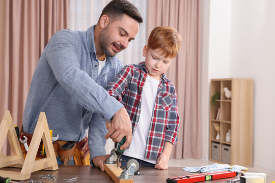 Father and son screwing wooden plank at home. Repair work