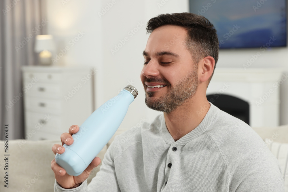 Poster Man drinking from light blue thermo bottle indoors